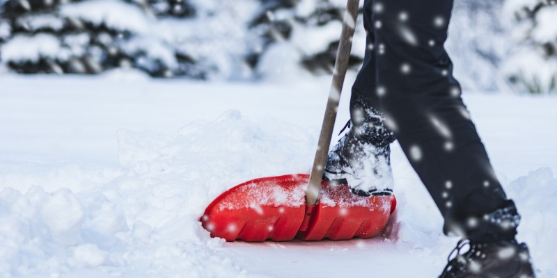 person shovelling snow with red shovel